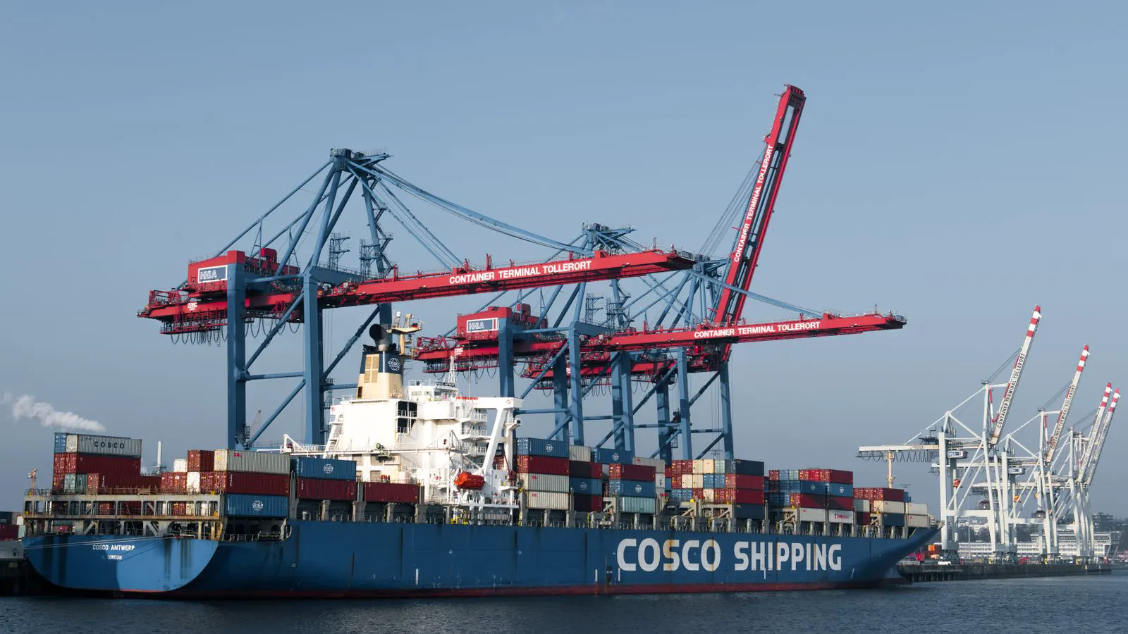 A large crane lifting a shipping container at a port terminal