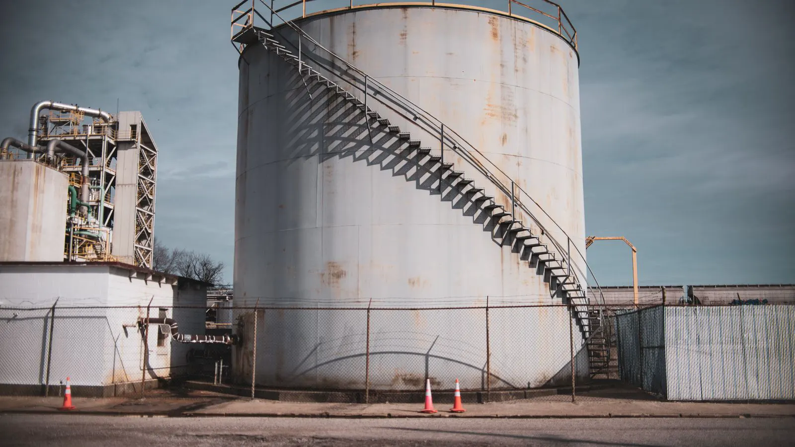 A large stainless steel chemical tank in an industrial yard.