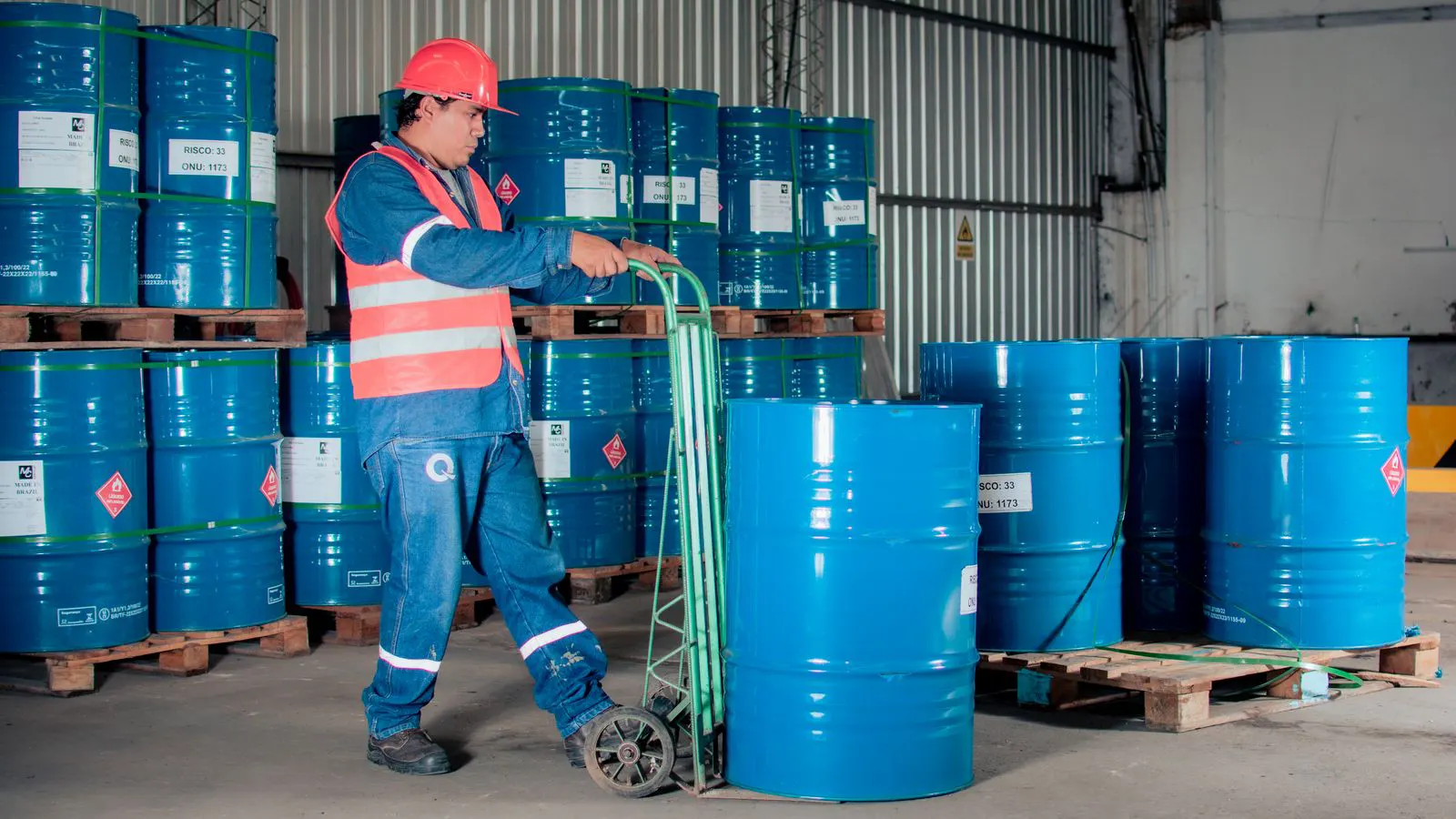 A large warehouse holding labeled chemical drums and storage racks.
