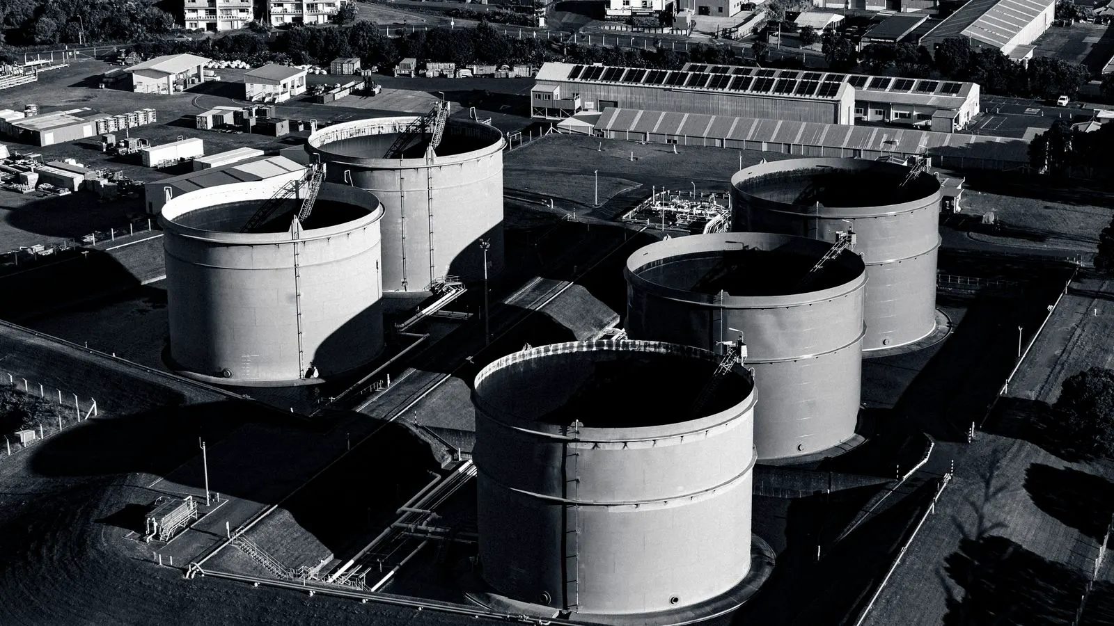 A row of large industrial chemical storage tanks in a warehouse.