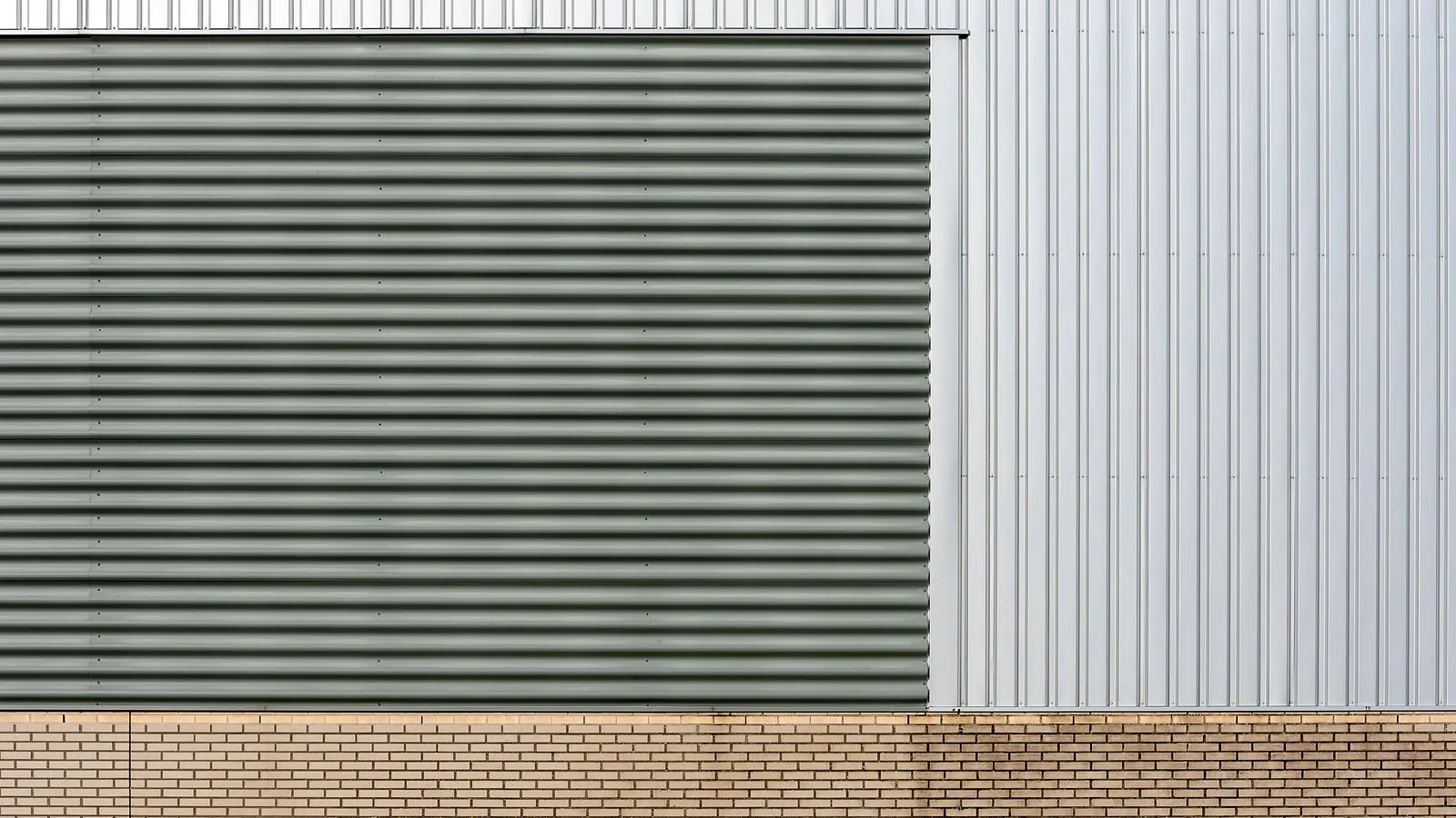 Weathered metal panel showing white powder residue and color loss under daylight