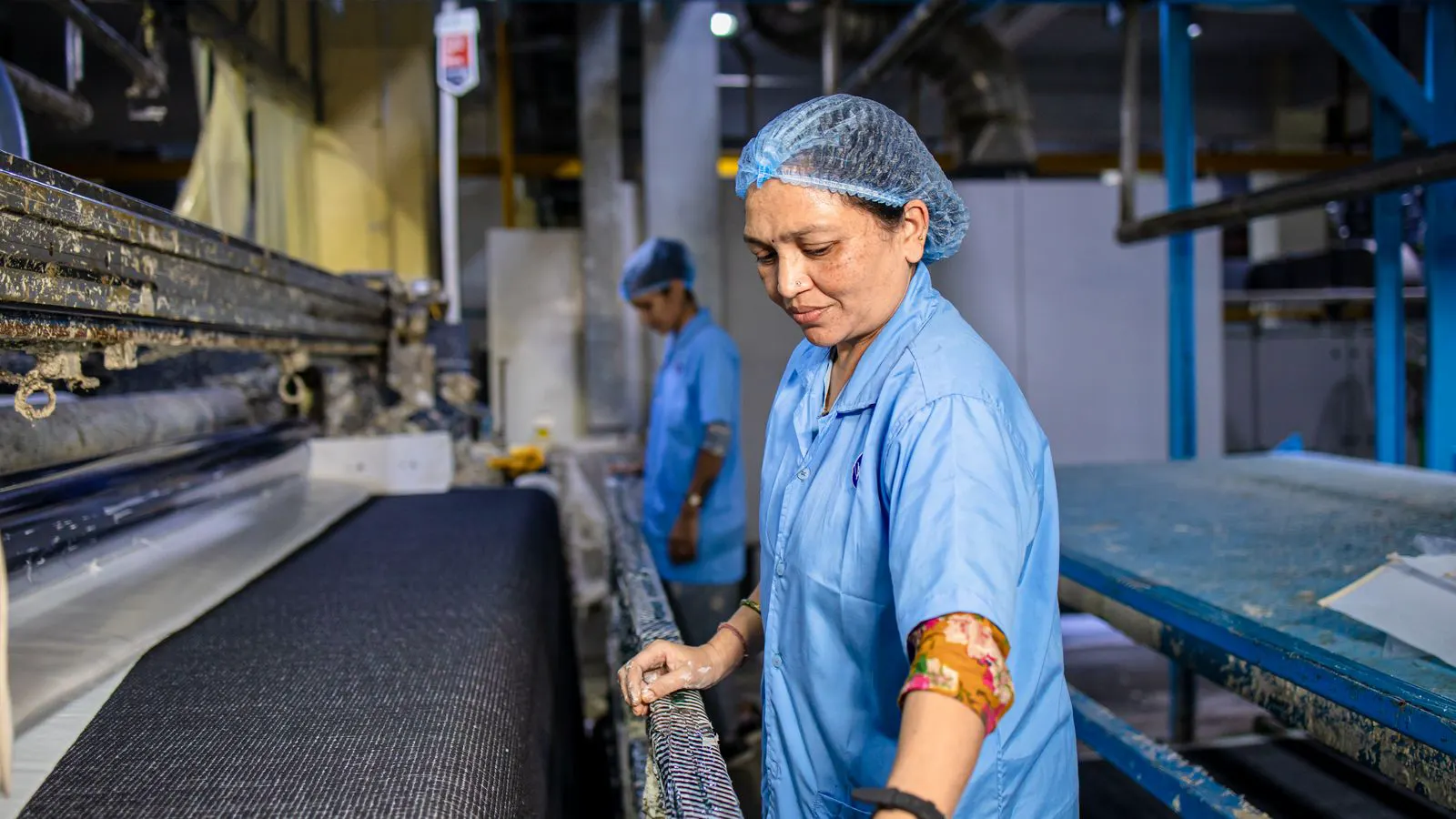 A technician inspecting a roll of carbon fiber prepreg in a clean room.