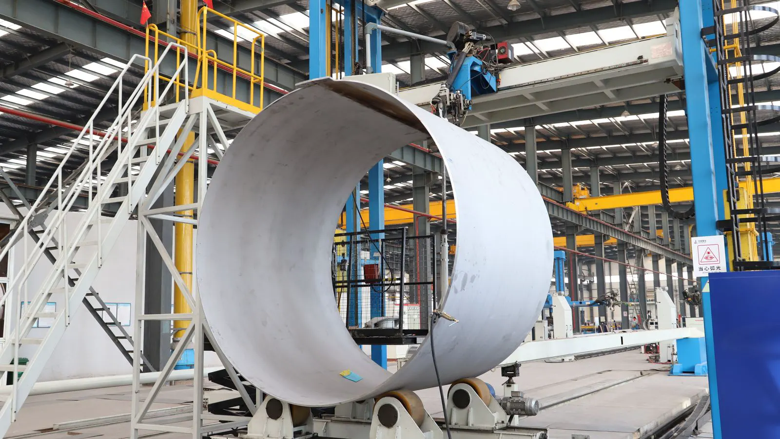 Workers assembling steel trusses inside a fabrication plant