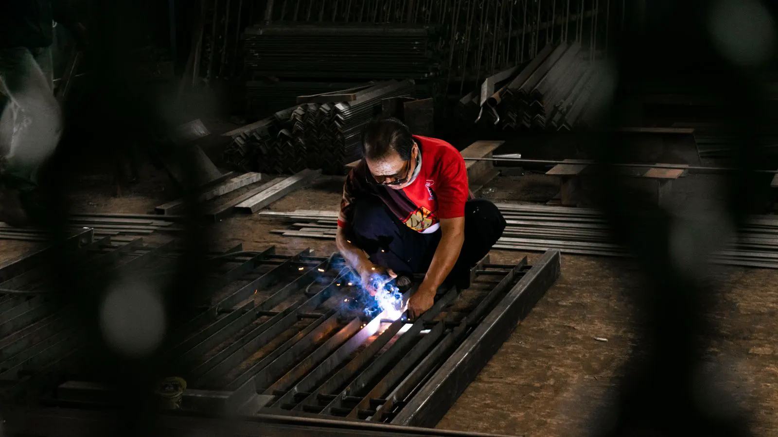 Workers welding steel beams inside a manufacturing facility.