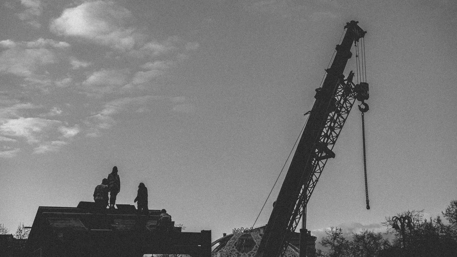 Workers positioning a steel beam with a crane on a construction site