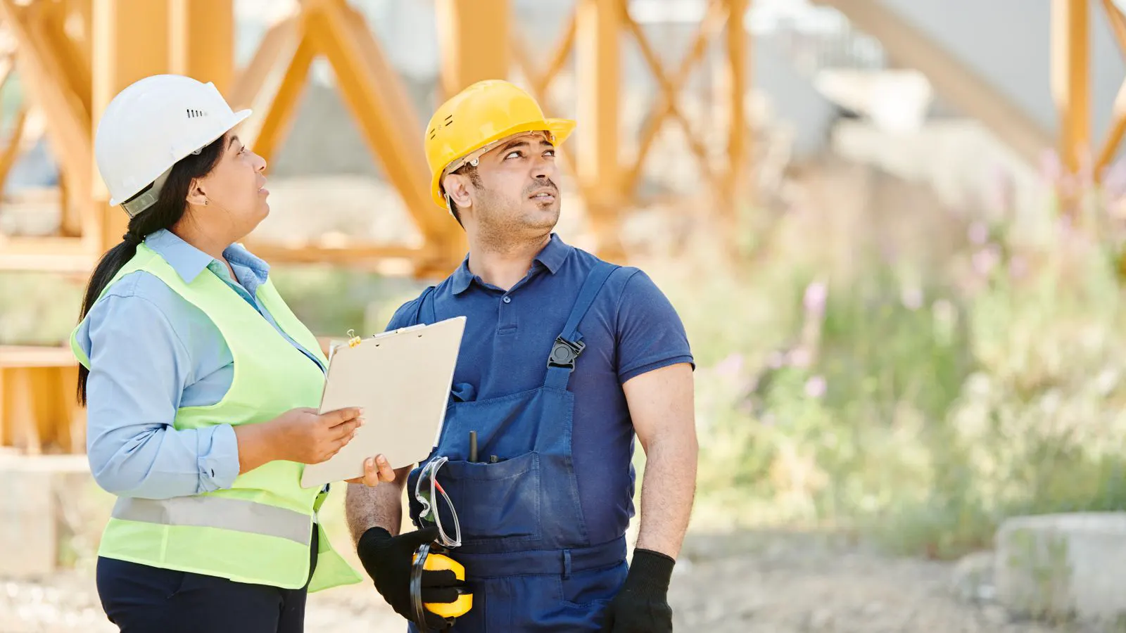 A clipboard with inspection forms next to a steel frame structure