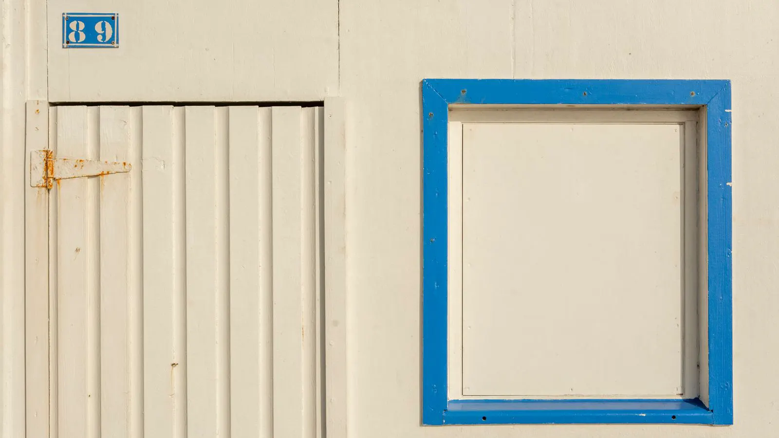 A metal hinge mounted on a heavy window frame