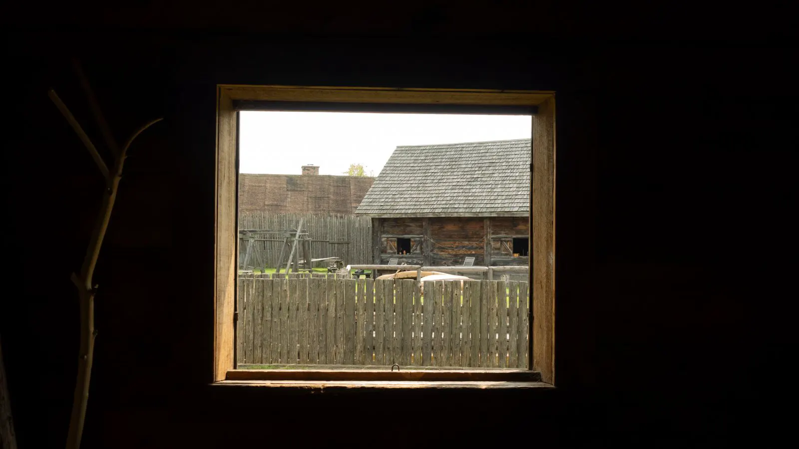 A white plastic frame stands beside a brown wooden window frame on a workbench.