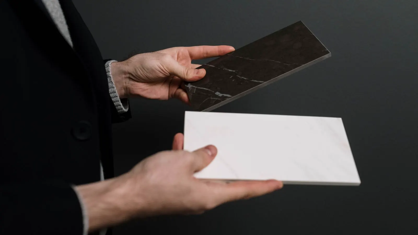 Hands holding a ceramic tile with visible surface scratches