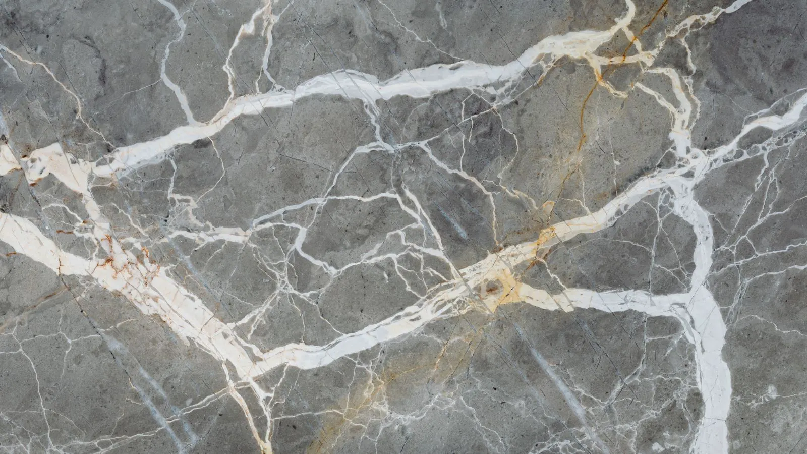 A worker inspects a marble slab under angled light to check for surface defects.
