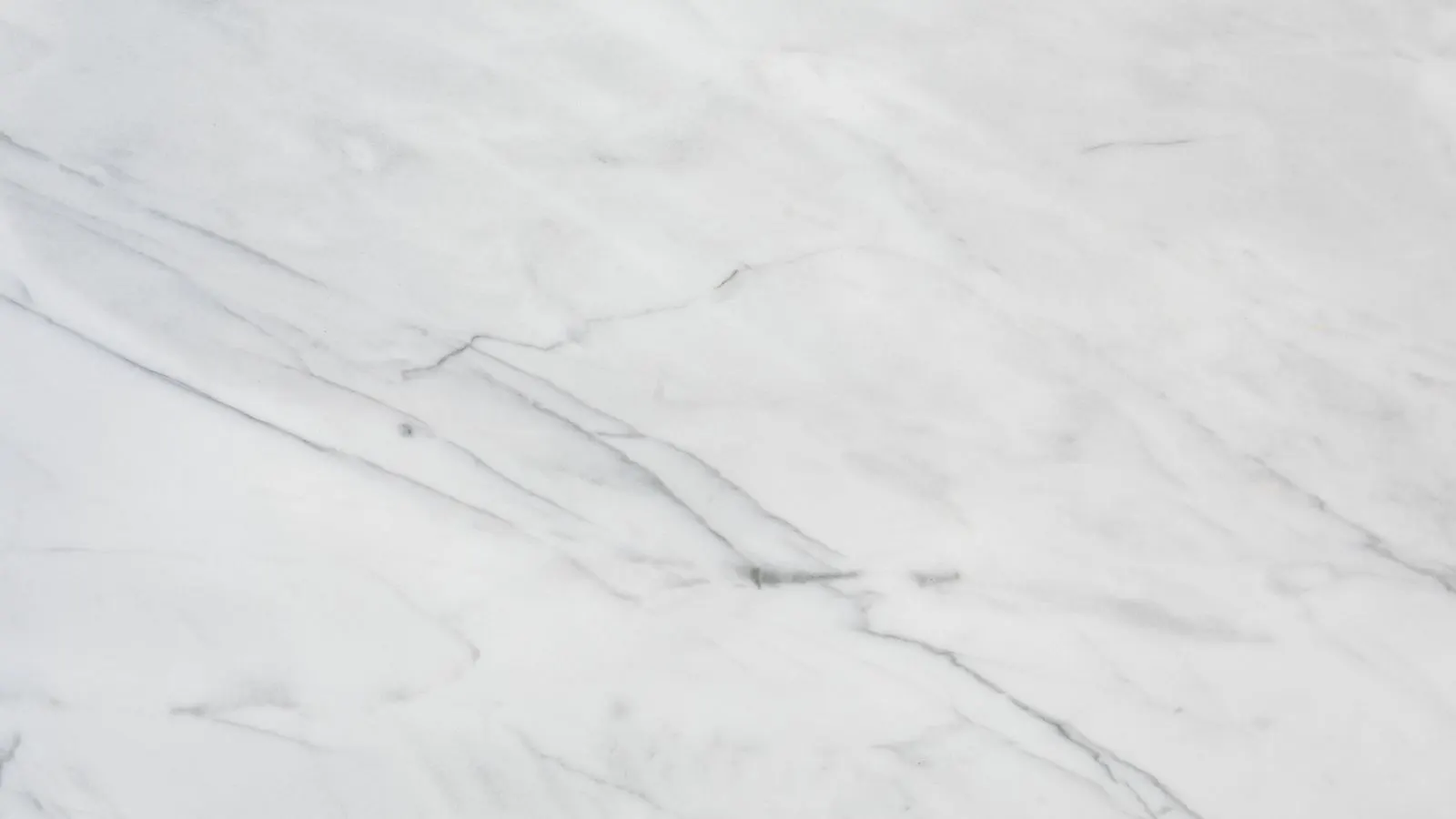 A close up view of a white marble countertop showing a dark circular stain