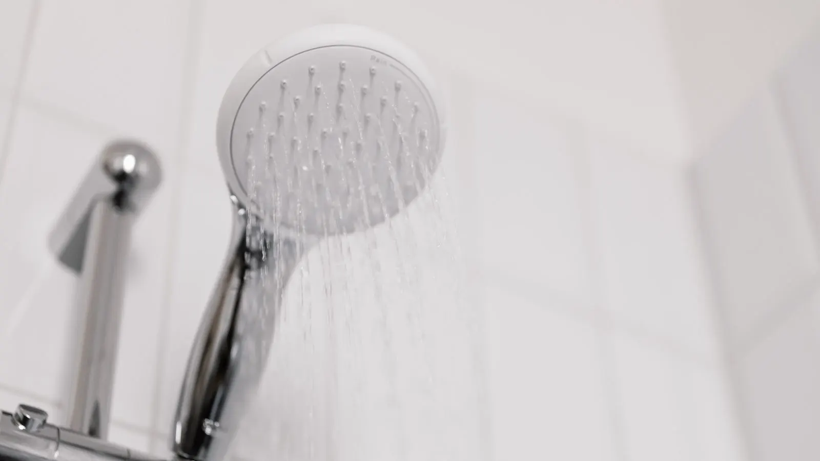 Close view of a chrome shower head with water flowing