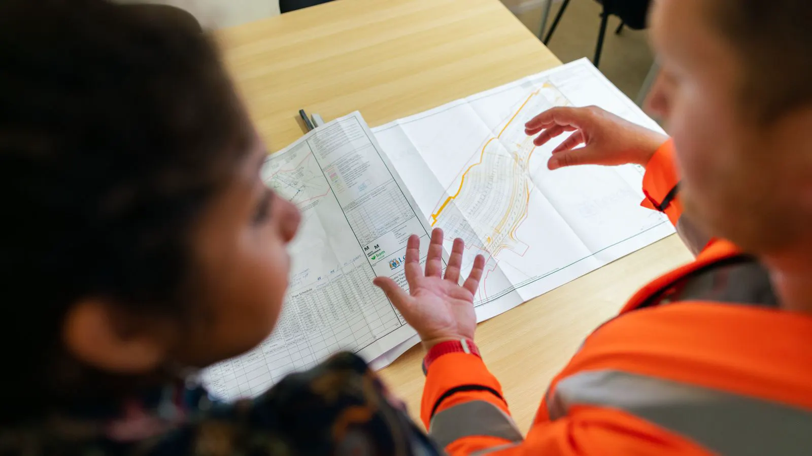 An engineer checks a thermal load calculation document at a drafting table