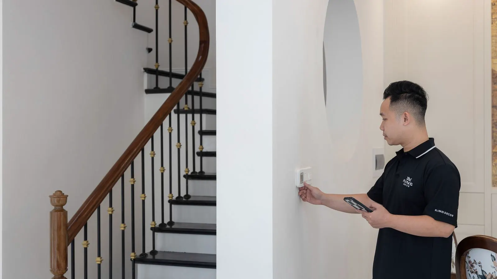 Technician checking a wall-mounted thermostat and sensor assembly.