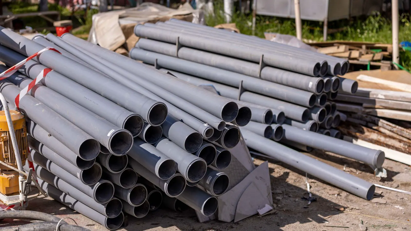 A side by side view of gray PVC and black PE pipe sections