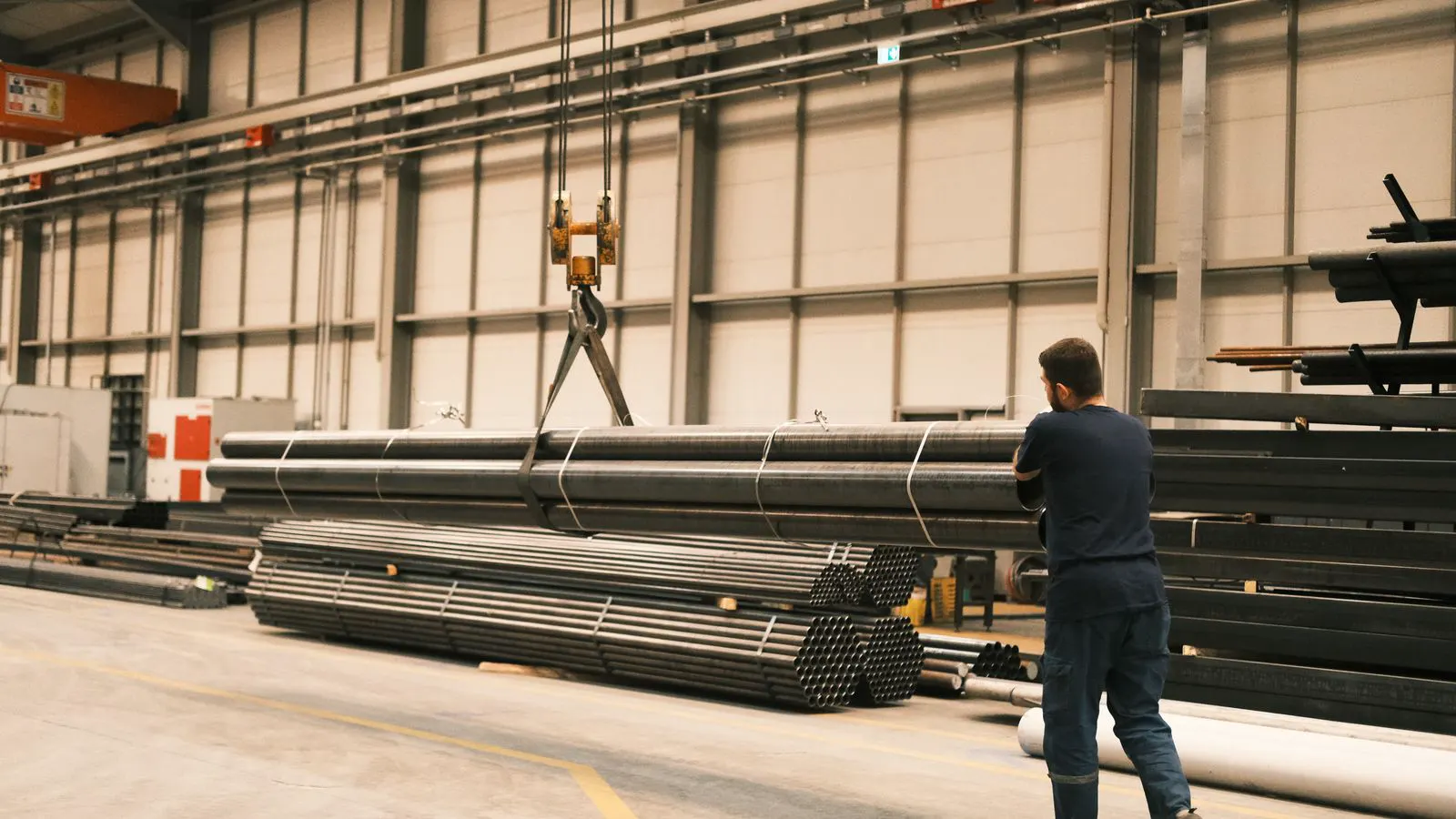 Piles of steel pipes stored in an open warehouse
