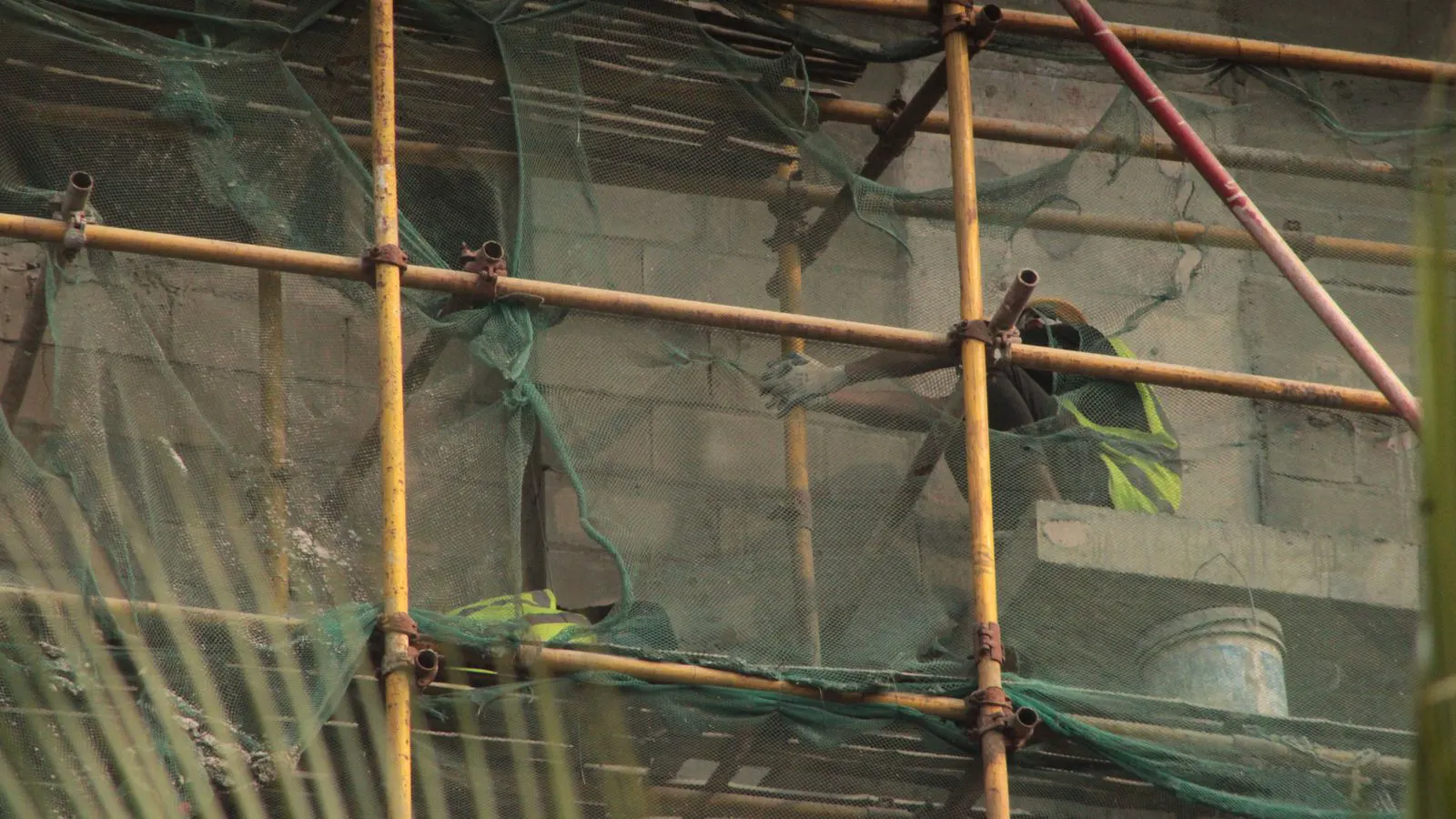 Workers inspecting a scaffold tower on a building site.