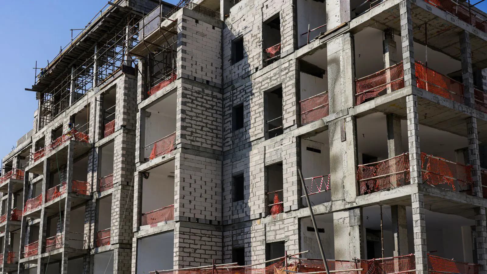 Worker holding a clipboard checks metal scaffold joint connections