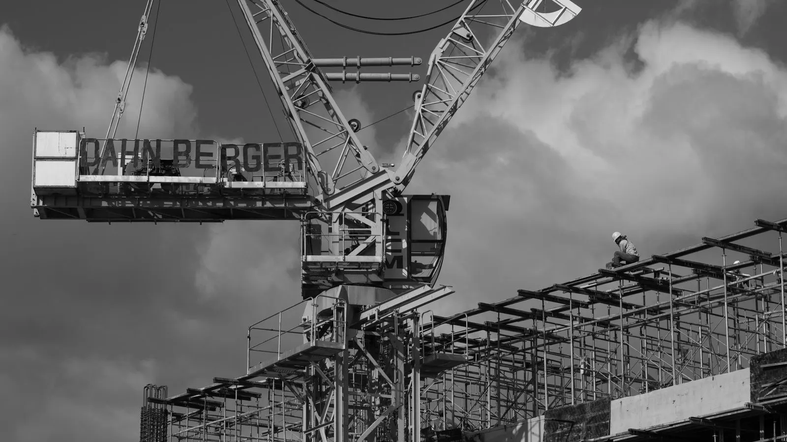 Workers inspecting a steel tower scaffold base on a concrete pad.