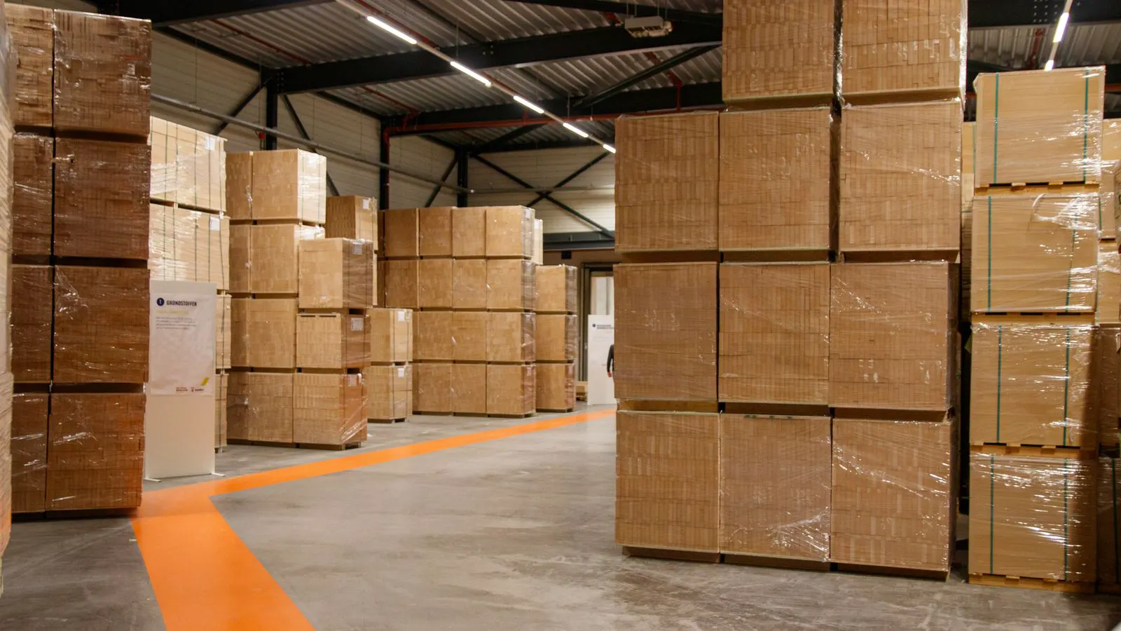 A vertical stack of brown corrugated boxes in a warehouse