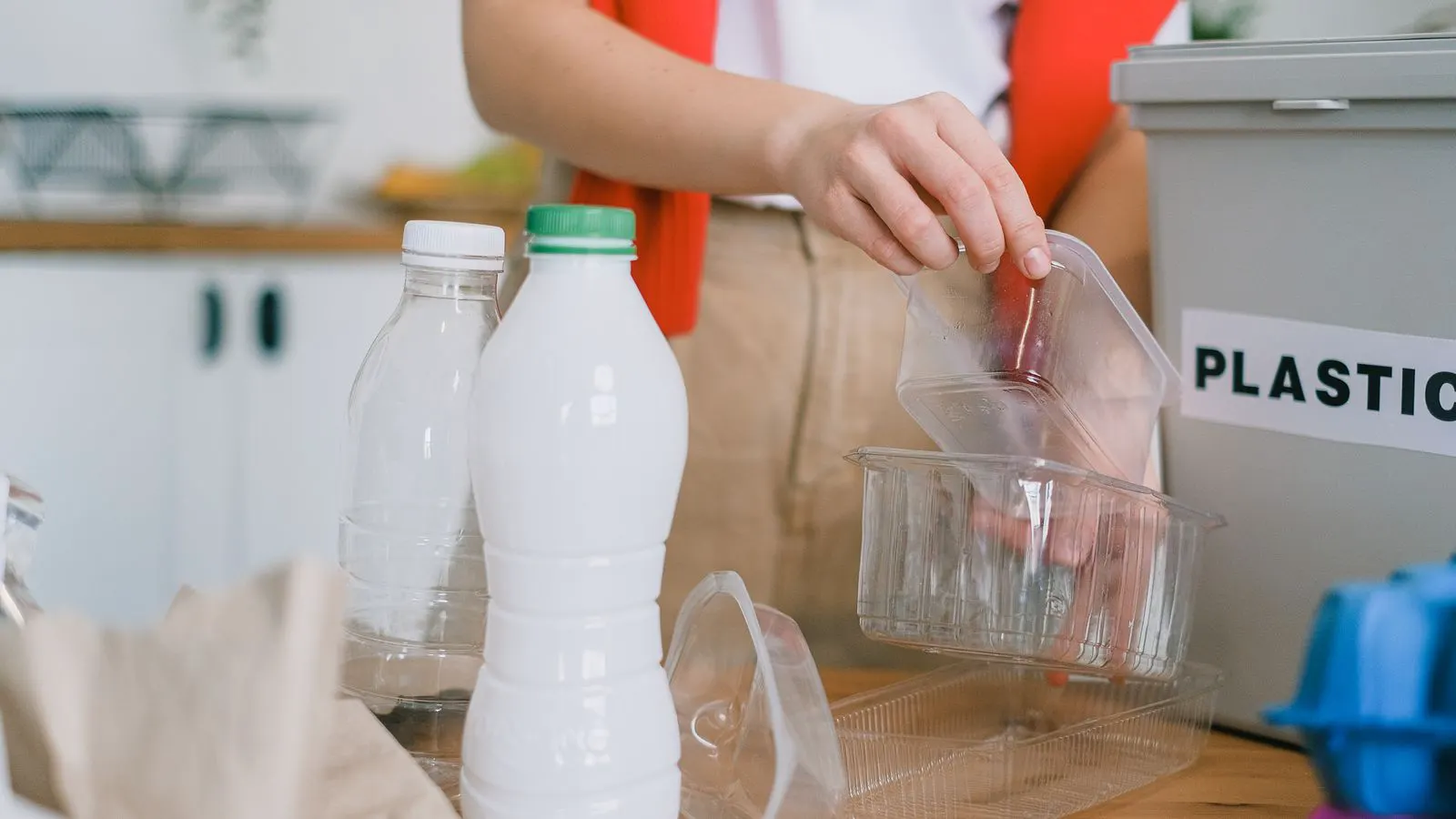 A clear glass bottle and plastic container sitting on a white surface.