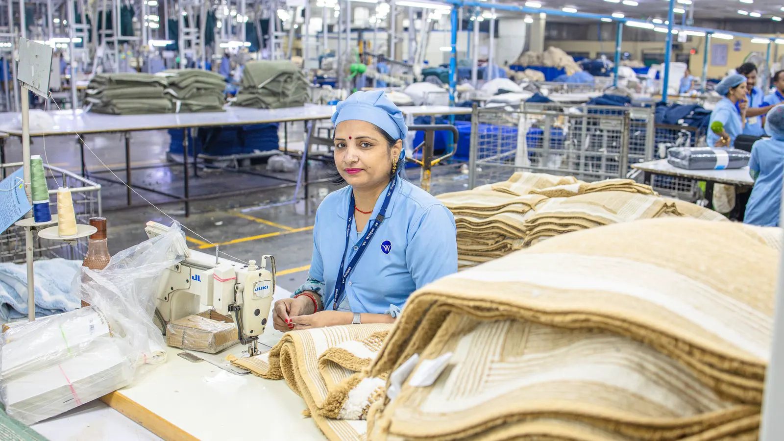 Large industrial looms running in a brightly lit textile production hall.