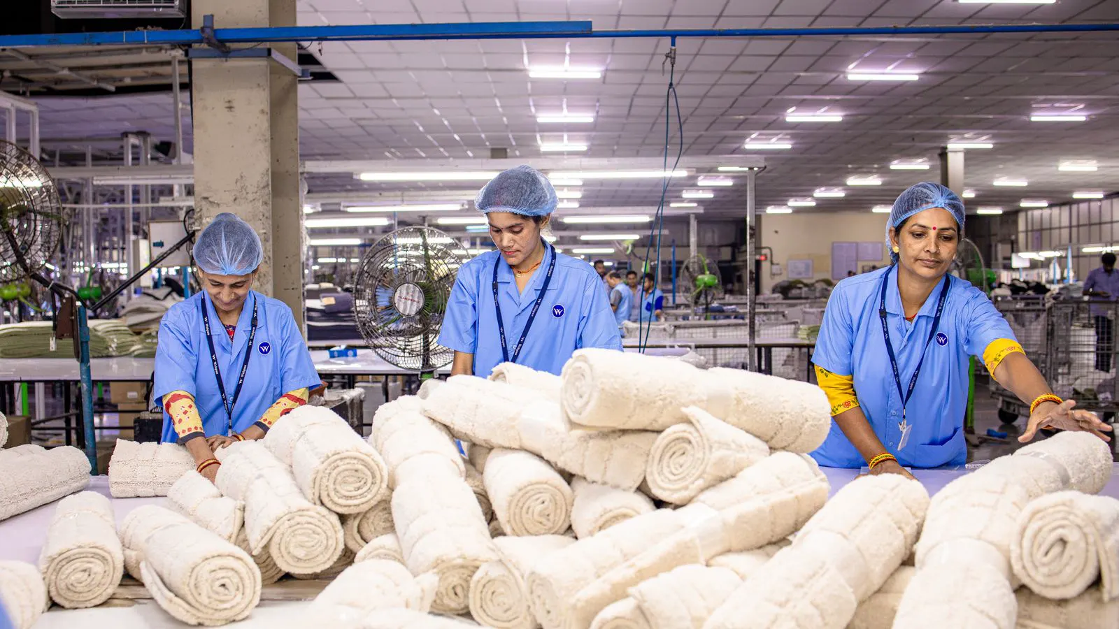 A large roll of white nonwoven fabric rests on a wooden pallet