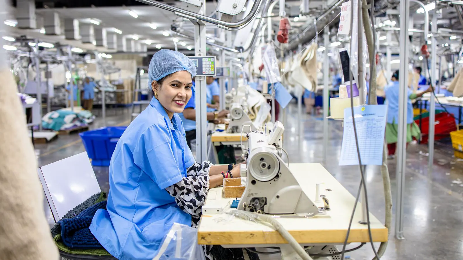 Workers operating sewing machines in a busy factory floor