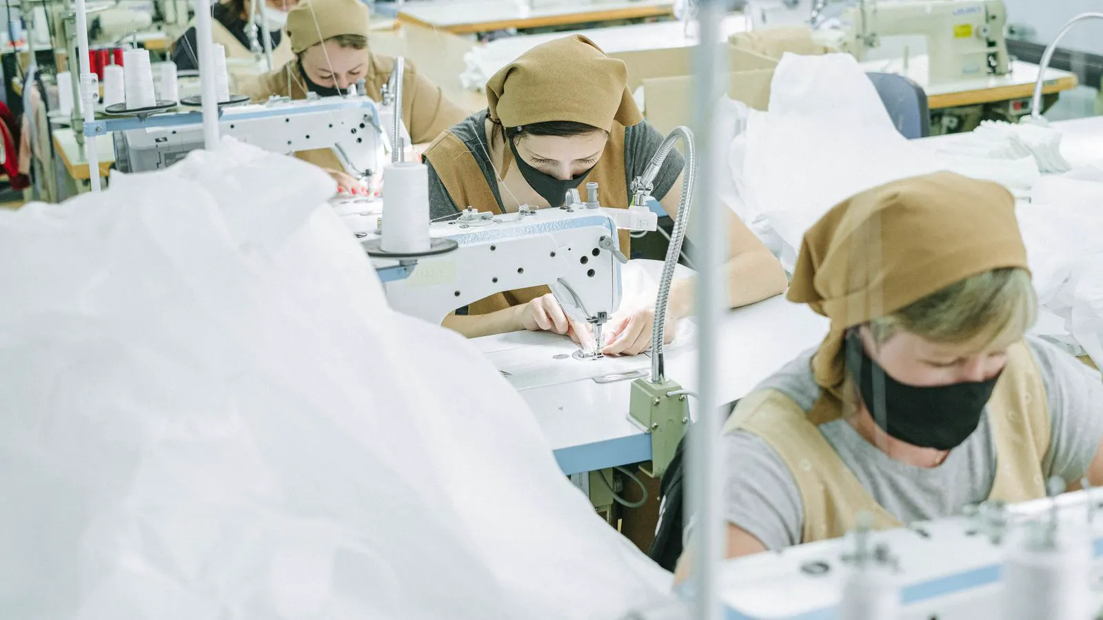 Garment workers operating sewing machines in a production line