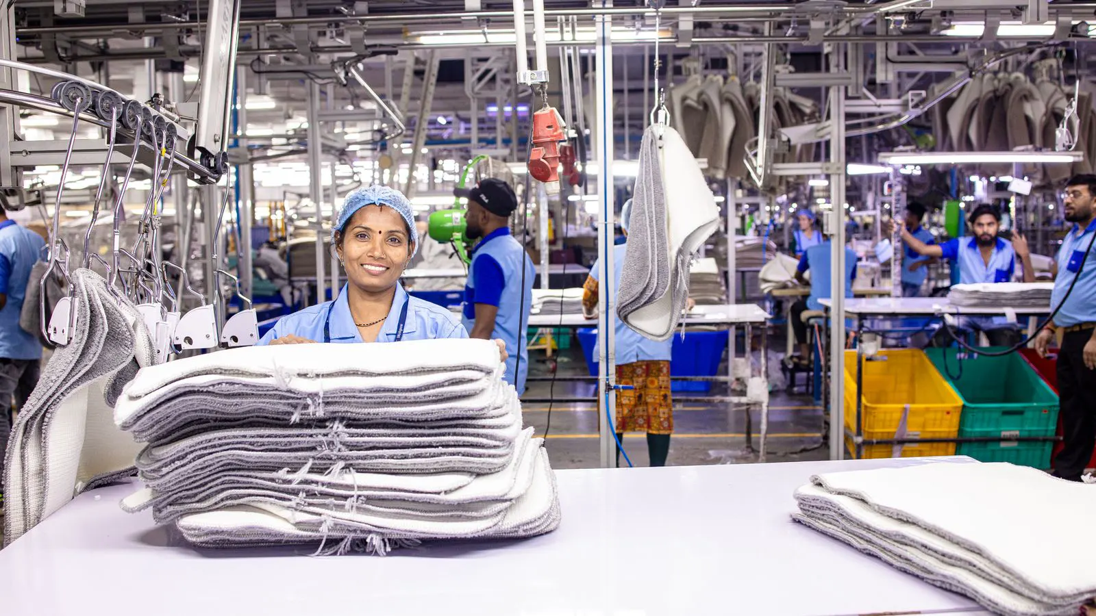 Workers inspecting fabric bolts at a garment cutting table