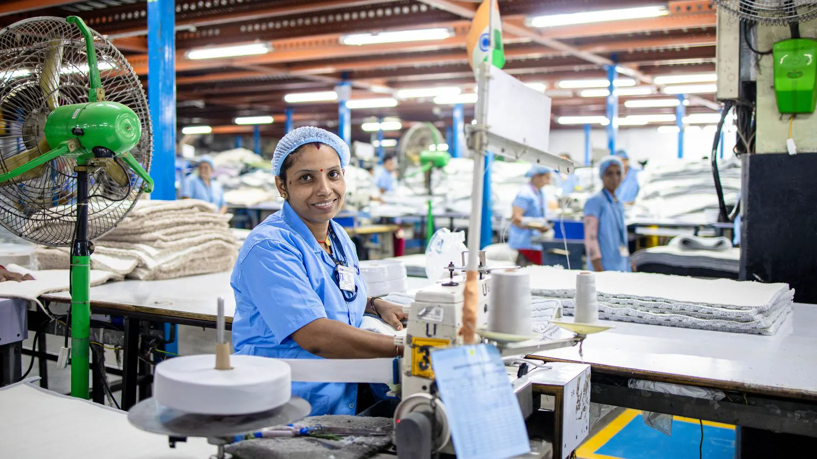 Workers operating a row of industrial sewing machines on a factory floor