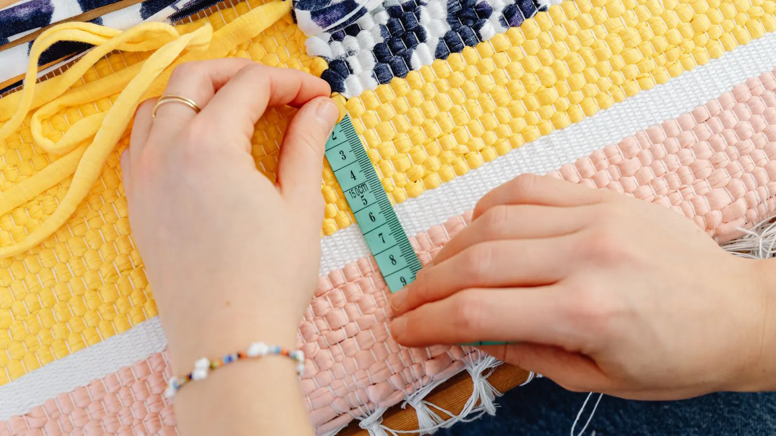 A hand using a counting grid to measure thread density on a fabric sample