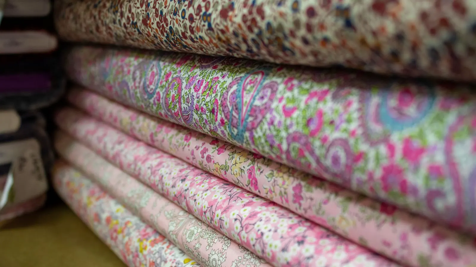 Rolls of cotton fabric stacked on a textile factory floor.
