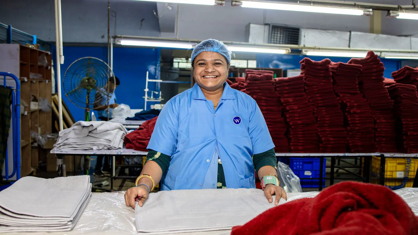 A worker inspecting fabric rolls in a textile warehouse