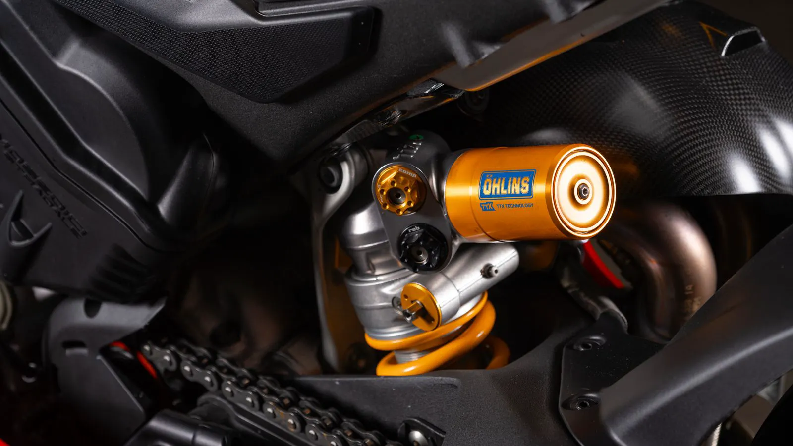 A close up view of a metal suspension arm bolted to a vehicle chassis
