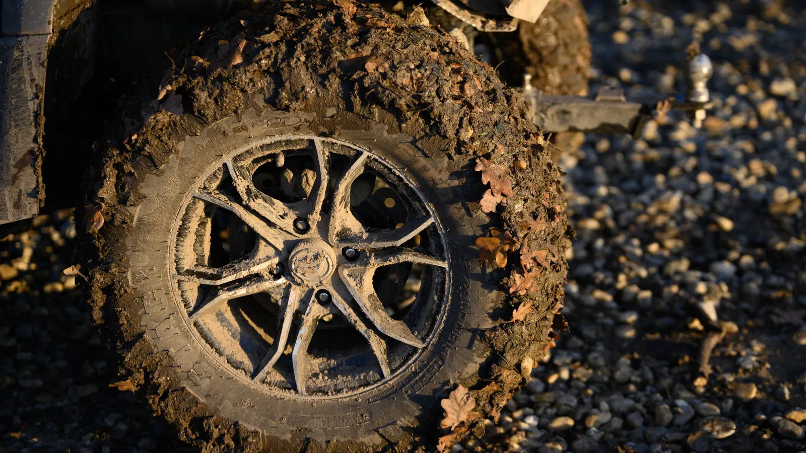 Two rugged tires caked in thick mud next to a rock outcrop