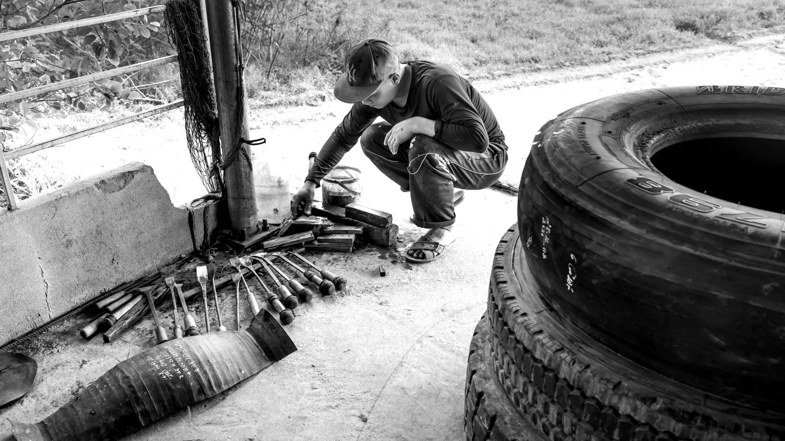 A worker in a warehouse checks a tire sidewall for damage.