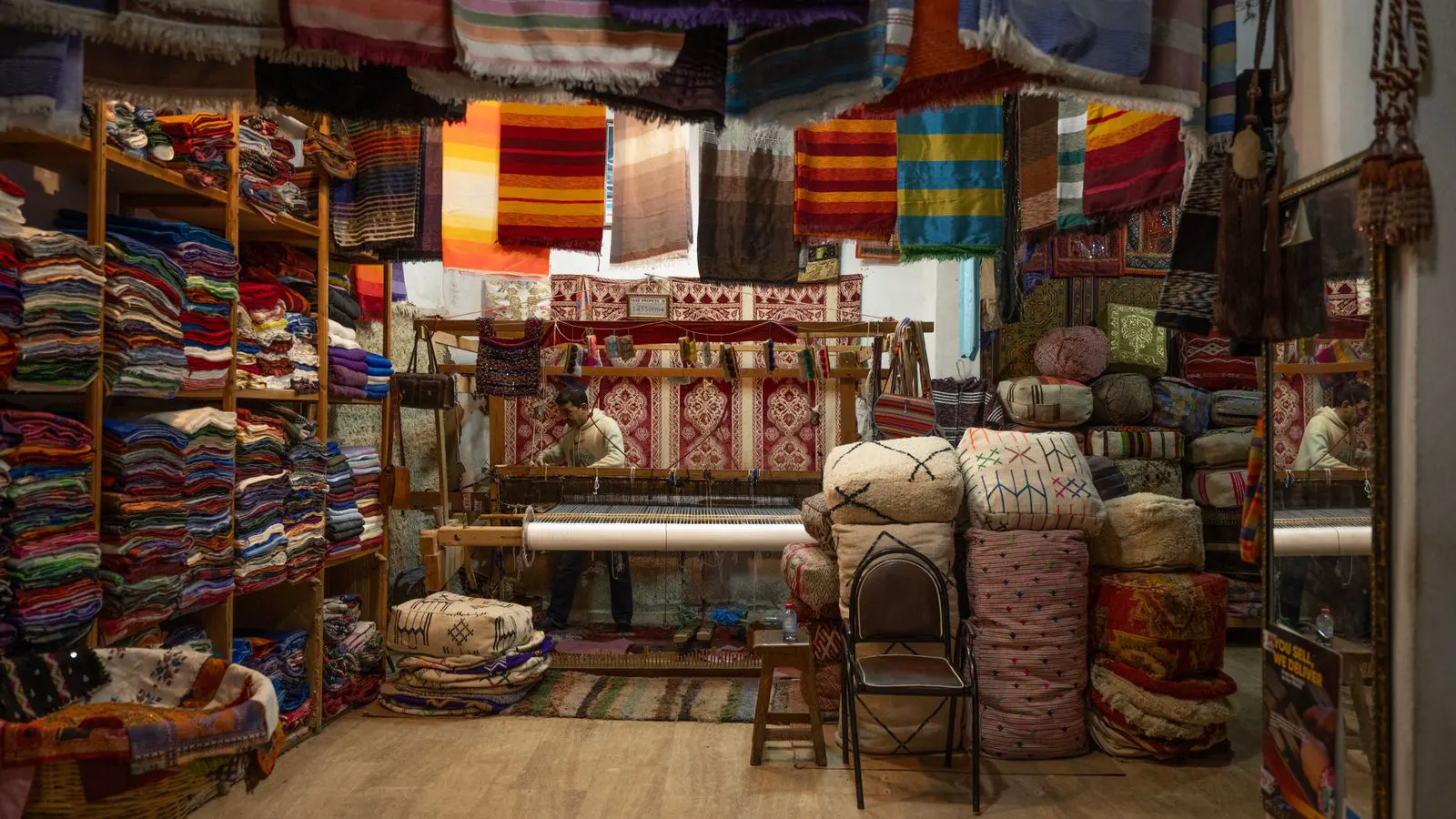 A large industrial loom producing colorful fabric rolls in a mill.
