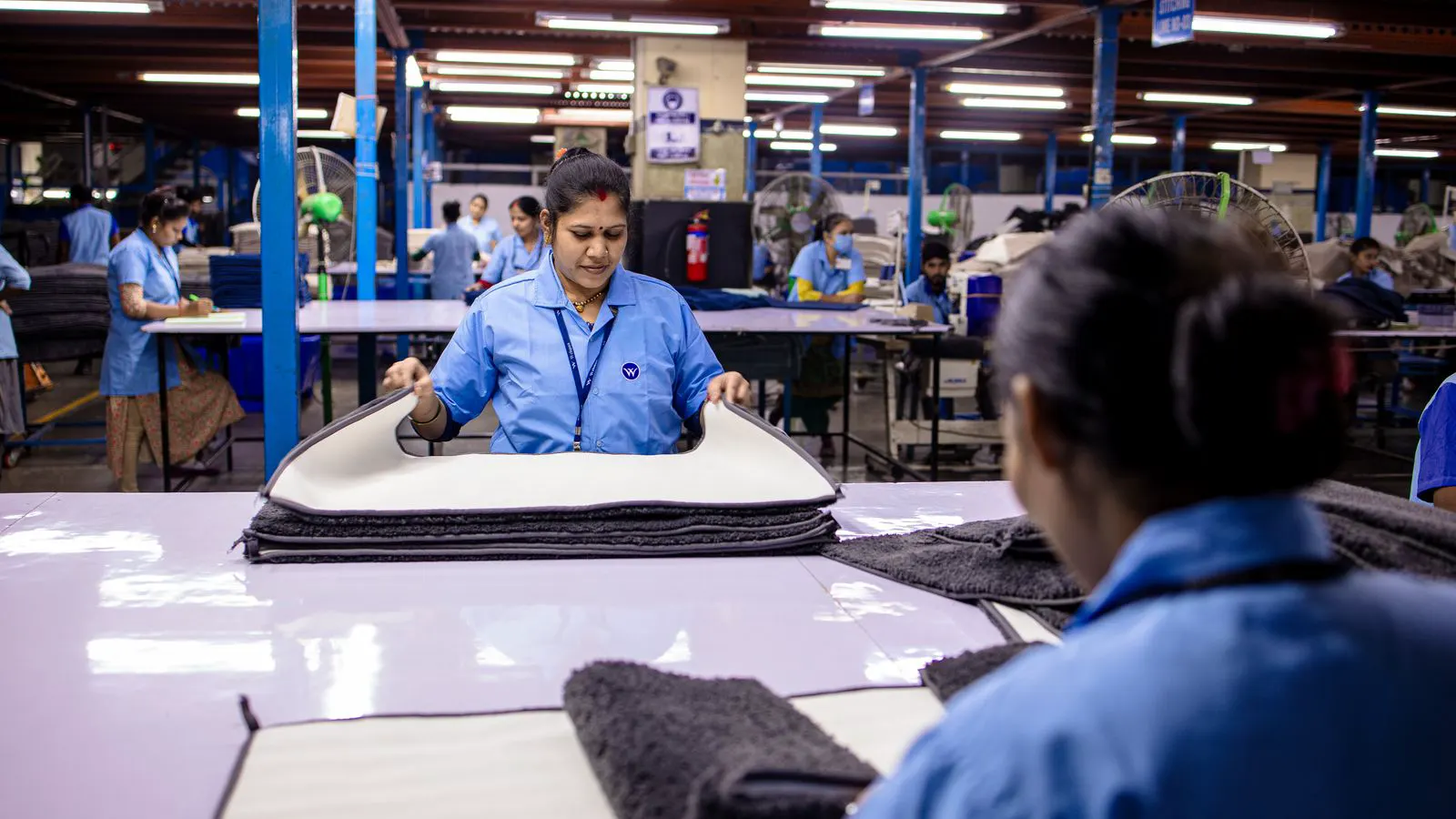 Workers inspecting frame joints and foam thickness on a sofa assembly line