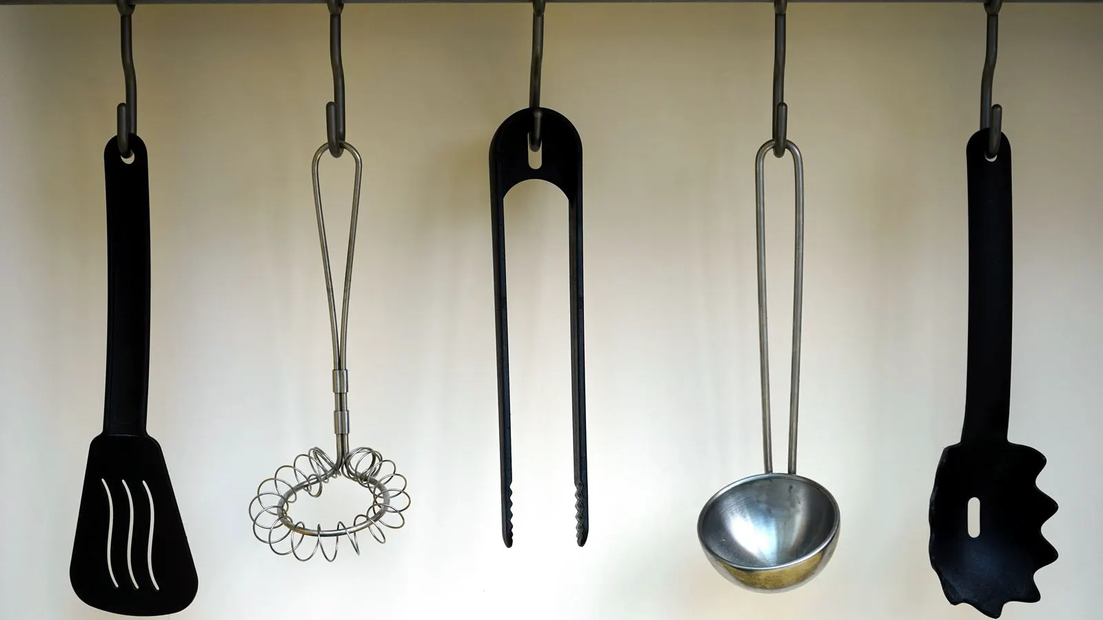 Assorted stainless steel cooking tools arranged on a clean white workbench surface.