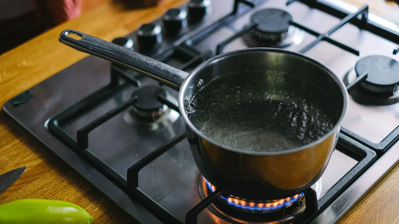A seasoned cast iron skillet and stainless steel saucepan sit side by side on a stainless counter.
