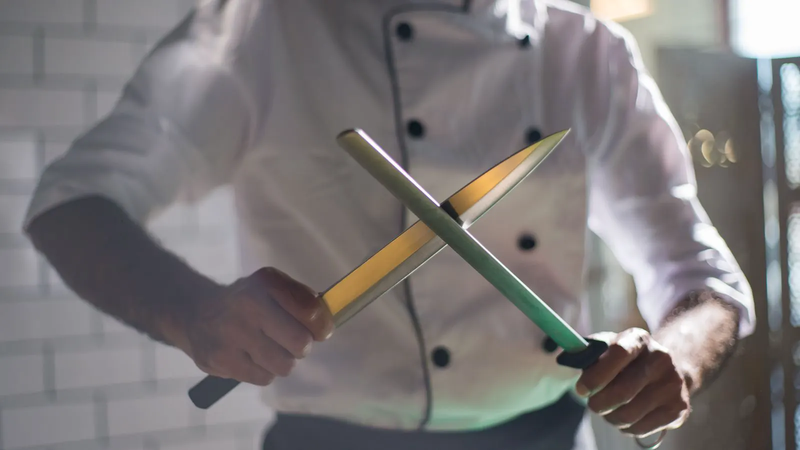 Close view of a chef knife blade resting on a cutting board.