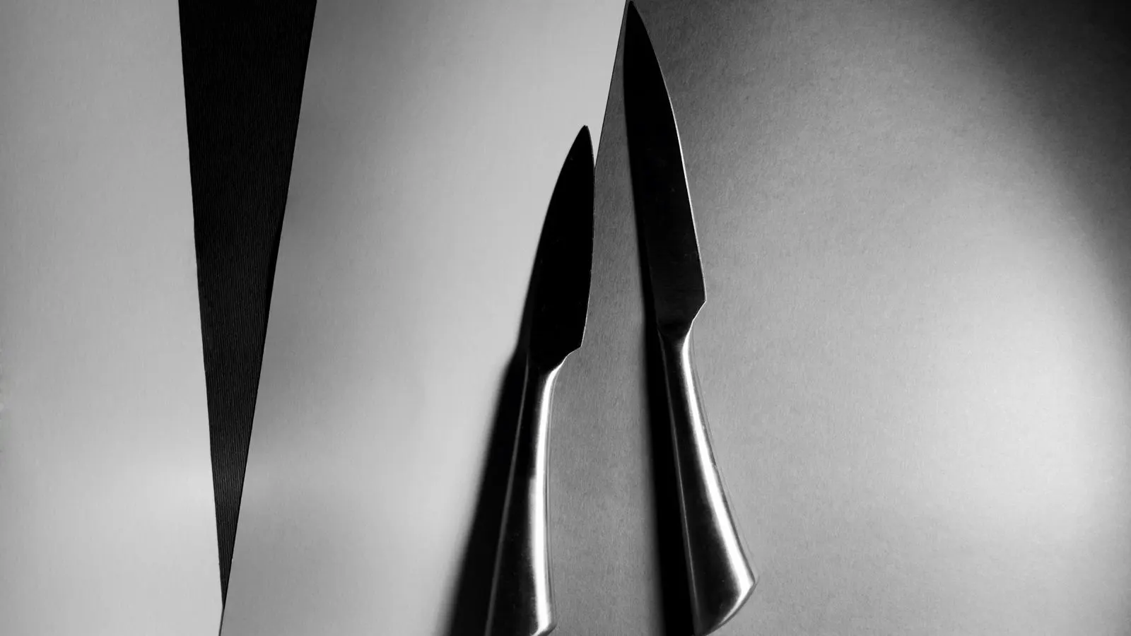 A row of surgical stainless steel knives resting on a metal tray.