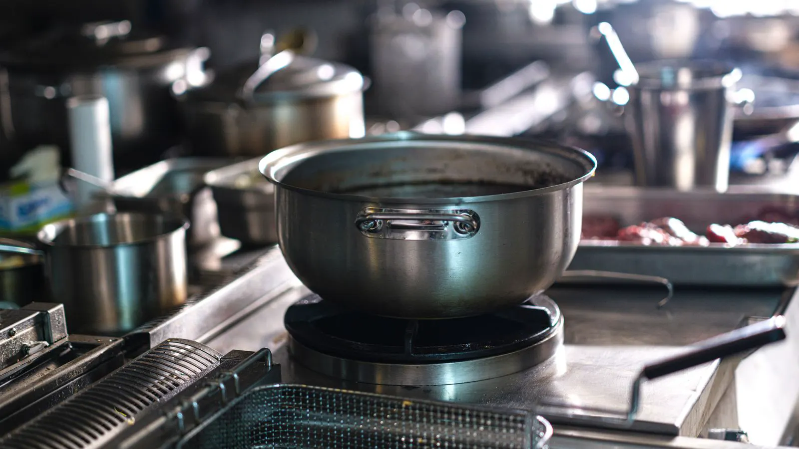 Stainless steel pans arranged on an industrial gas stove.