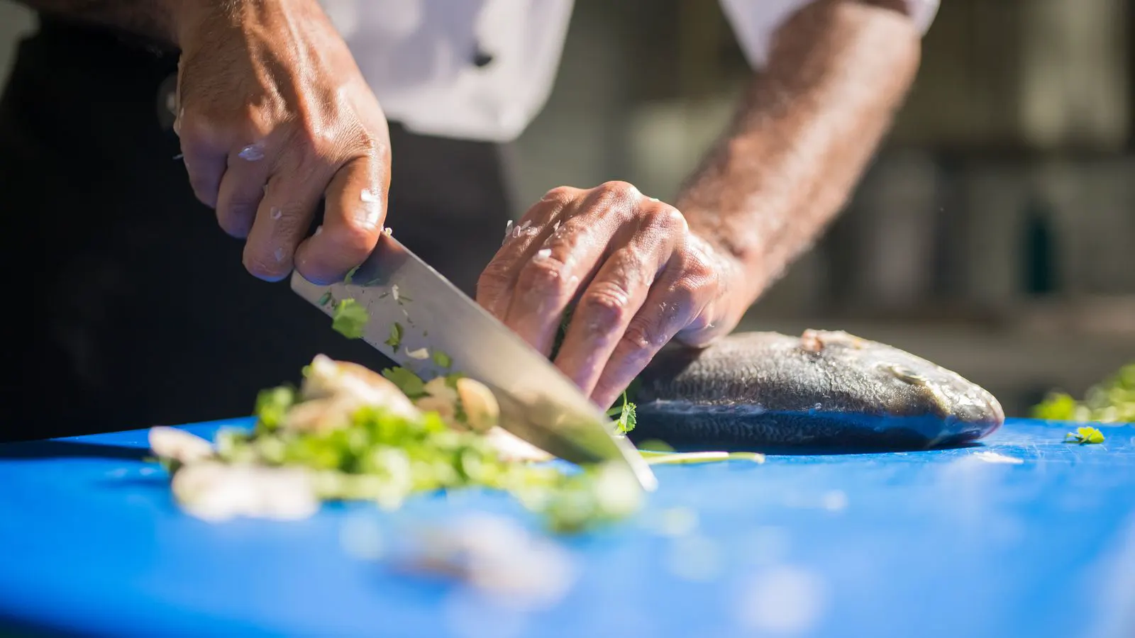 Two professional knives resting on a wooden cutting board