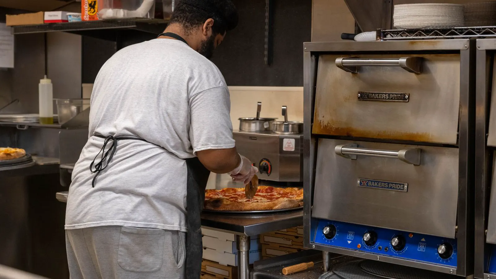 A tight commercial kitchen aisle between a prep table and a wall