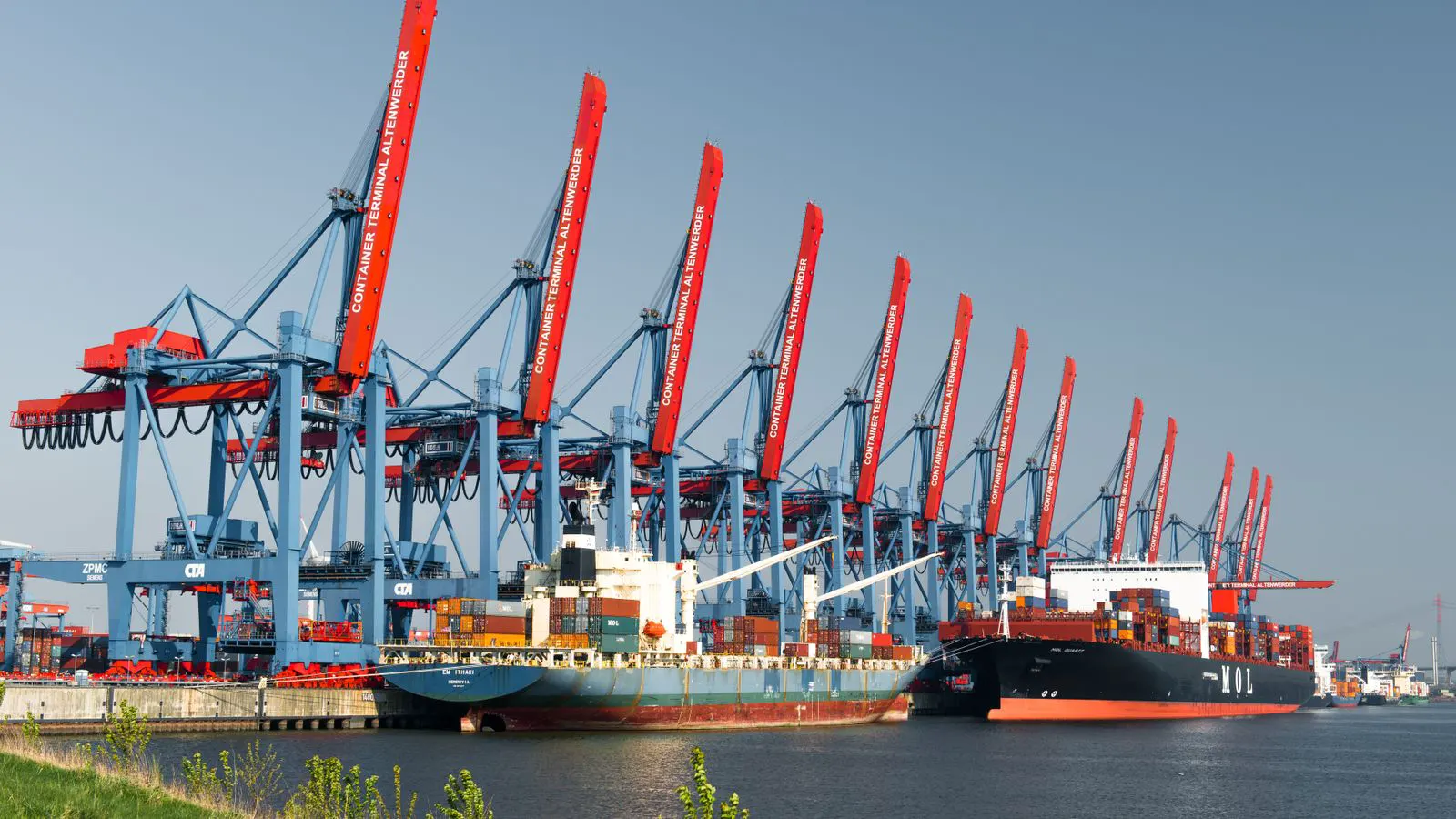 Shipping containers stacked near a port crane in a secure industrial yard