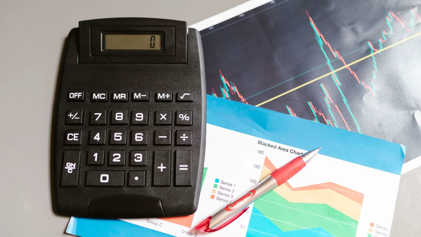A desk with printed cost estimates, a calculator, and a lab notebook