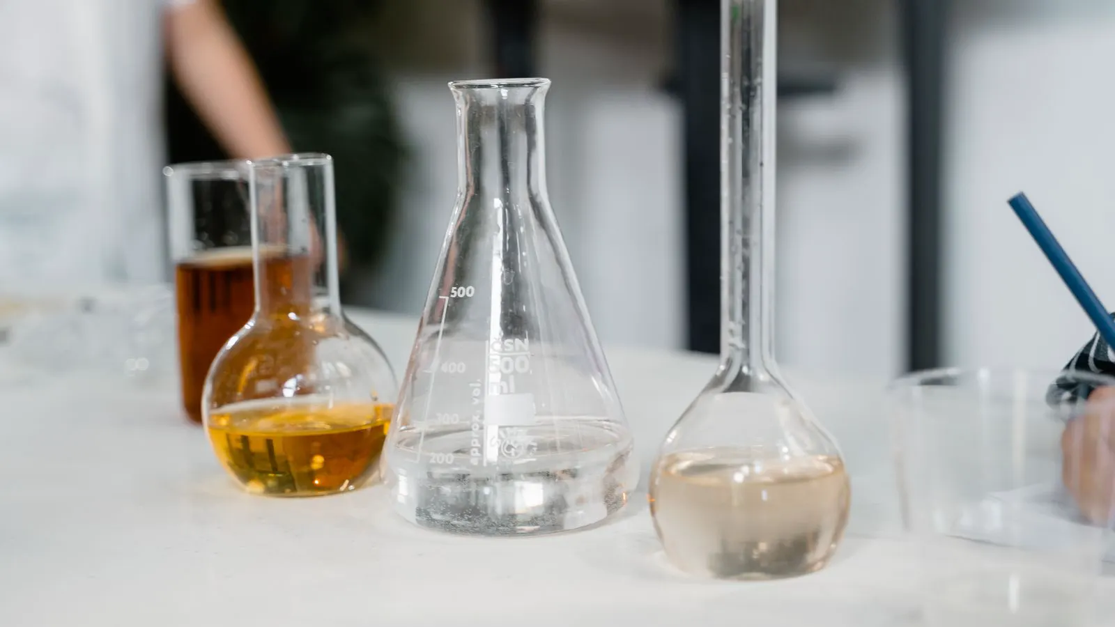 Several clear borosilicate beakers sitting on a lab bench.