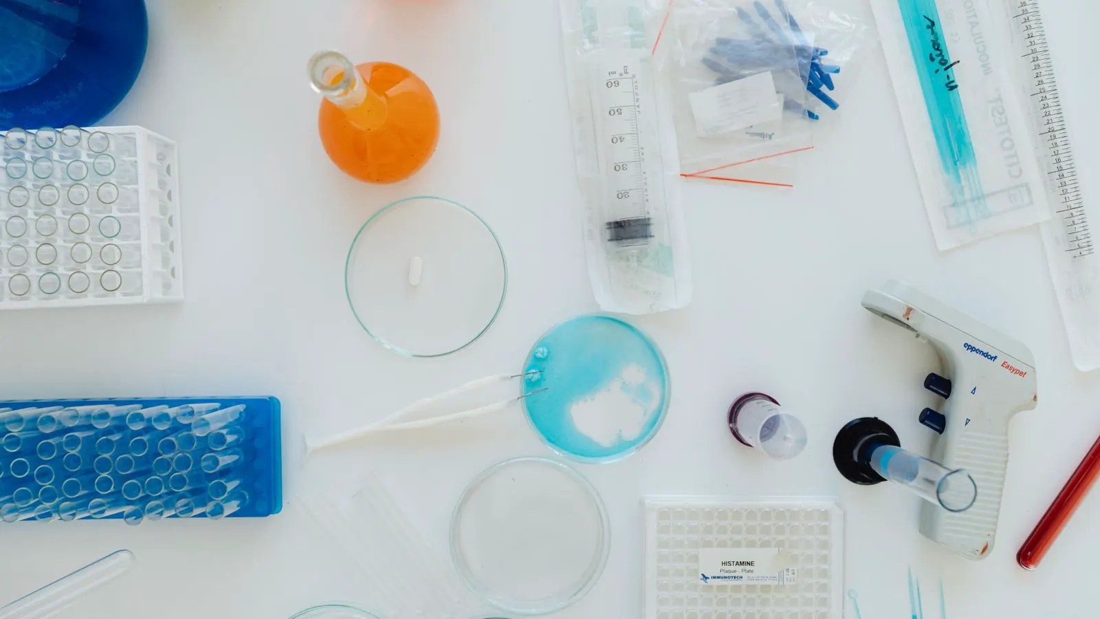 Laboratory bench with glass vials and plant-derived powder samples for cosmetic formulation research.